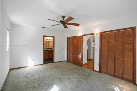 an empty room with closet and a ceiling fan