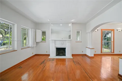 wooden floor fireplace and windows in an empty room