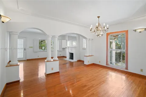 a view of a livingroom with furniture wooden floor a chandelier and windows