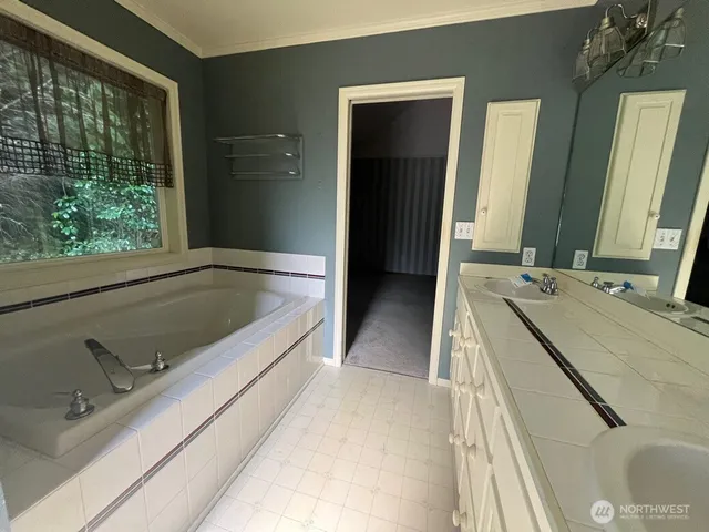 a spacious bathroom with a tub sink and mirror