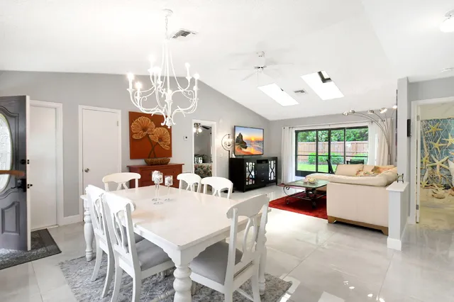 a view of a dining room and livingroom with furniture wooden floor a chandelier