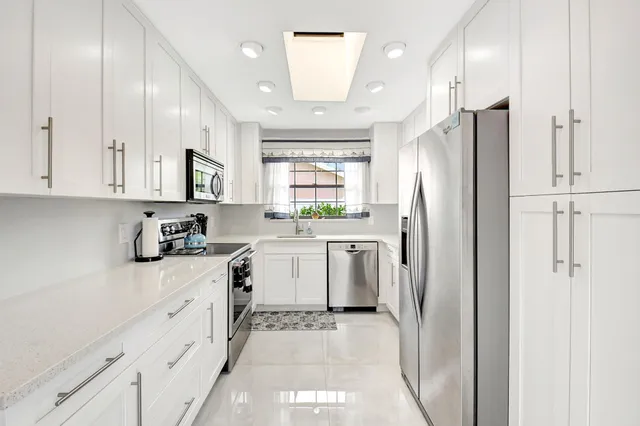a kitchen with white cabinets appliances and a sink