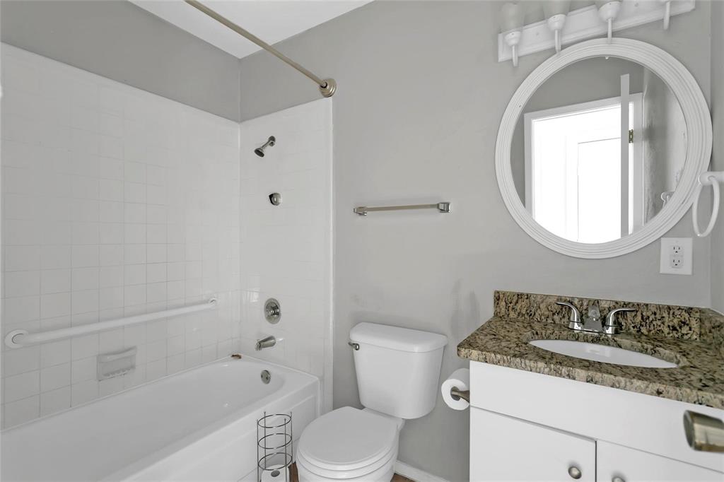 6104 Kelly Elliott Road Arlington, TX 76001 - Photo 8 of 25 a bathroom with a granite countertop toilet a sink and a mirror