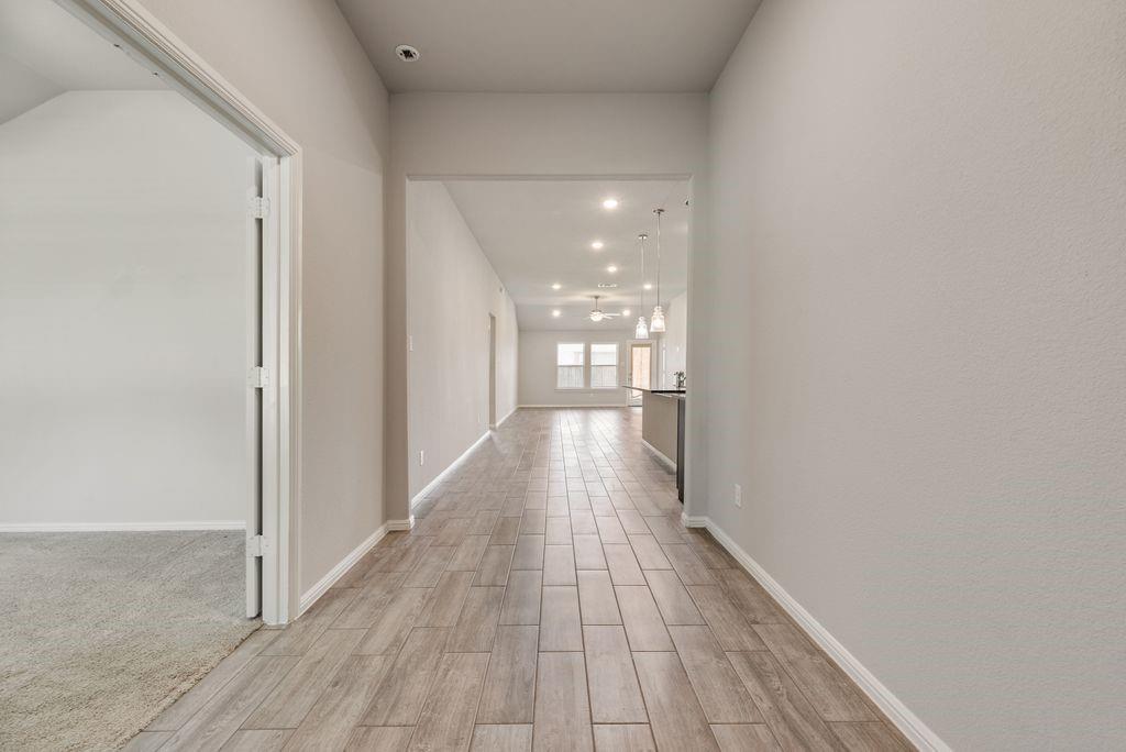 14216 Aberavon Drive Pilot Point, TX 76258 - Photo 3 of 19 Long hallway featuring wood-finish tile flooring, recessed ceiling lighting, and light gray wall paint