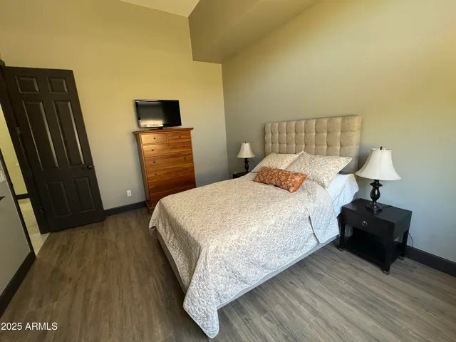 a bedroom with a bed a mirror on dresser and a wooden floor