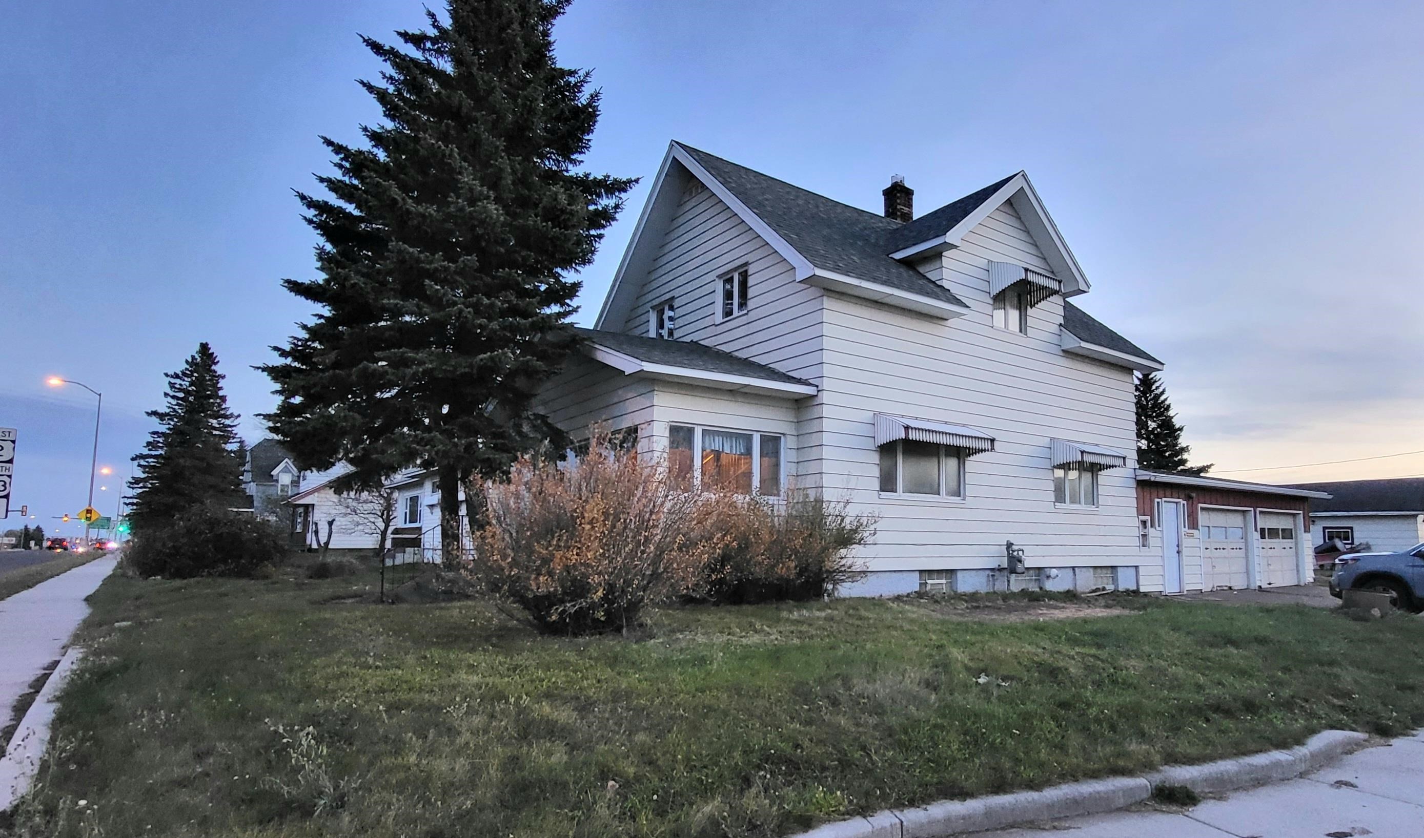View of side of home featuring a garage, a shingled roof, a chimney, and a lawn