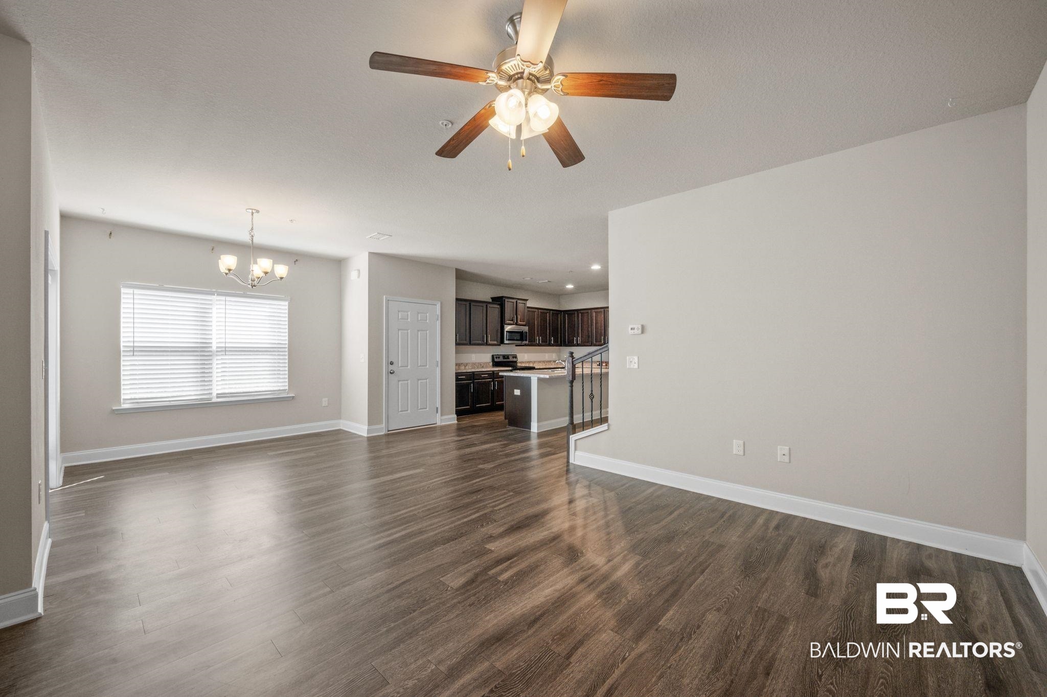 6903 Spaniel Drive, Unit B Spanish Fort, AL 36527 - Photo 8 of 28 Unfurnished living room featuring ceiling fan with notable chandelier, dark wood-style flooring, and baseboards