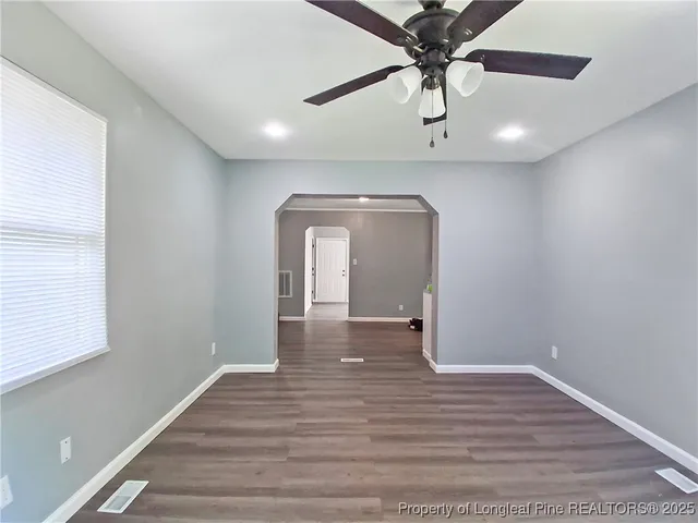 a view of a hallway with wooden floor and a chandelier fan