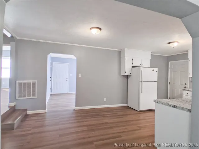 a view of a kitchen with refrigerator and wooden floor