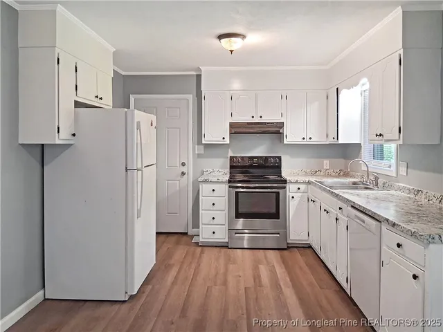 a kitchen with granite countertop a refrigerator stove and white cabinets