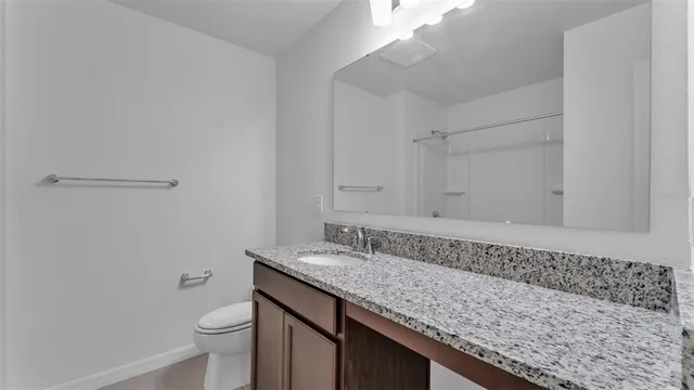 a bathroom with a granite countertop sink and a toilet