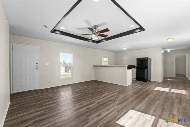 a view of a livingroom with a ceiling fan wooden floor and a ceiling fan