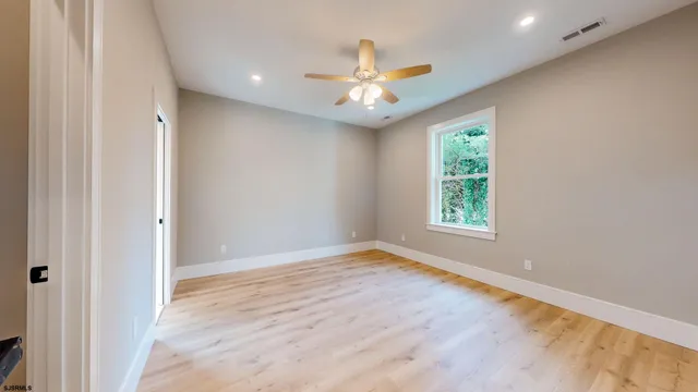 an empty room with windows and ceiling fan