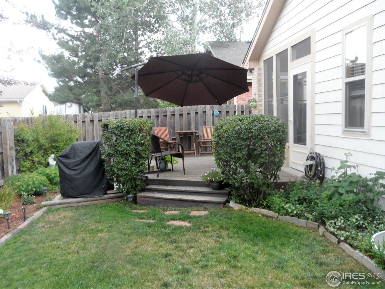 724 Wade Road Longmont, CO 80503 - Photo 29 of 32 a view of a chair and table under an umbrella in backyard
