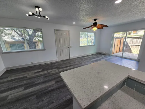 an empty room with windows and ceiling fan