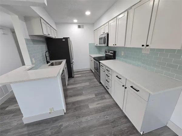 a kitchen with white cabinets and stainless steel appliances