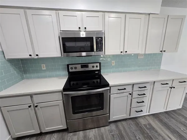 a kitchen with white cabinets and black appliances