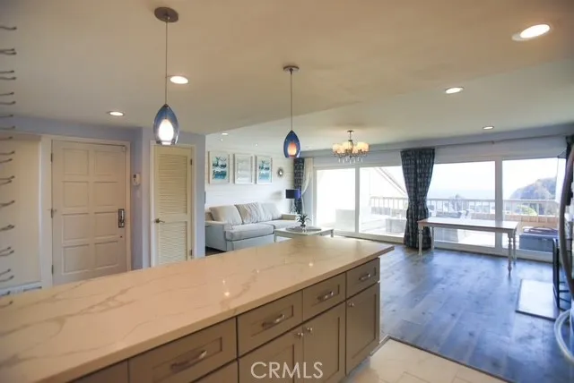 a open kitchen with stainless steel appliances granite countertop a sink dishwasher a stove and a dining table with wooden floor