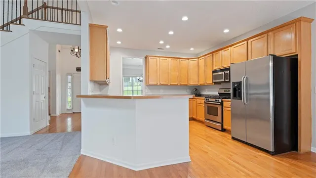 a kitchen with stainless steel appliances granite countertop a refrigerator a stove a sink and a microwave