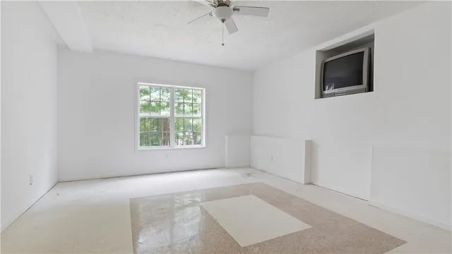 an empty room with windows and fan