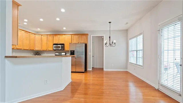 a kitchen with granite countertop stainless steel appliances a refrigerator cabinets and wooden floor