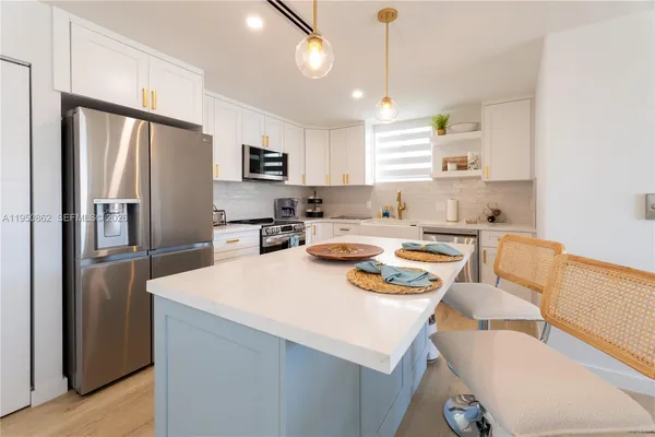 a kitchen with stainless steel appliances a refrigerator a sink a stove a dining table and chairs