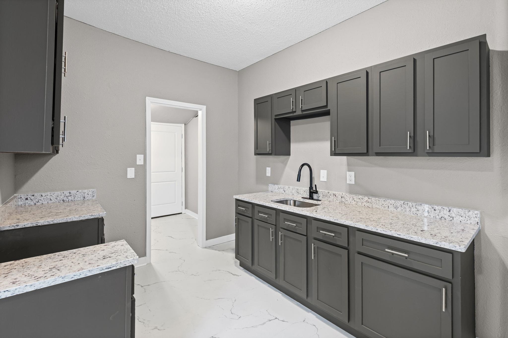 1503 Swift Street Memphis, TN 38109 - Photo 12 of 17 a kitchen with a sink dishwasher a stove and a refrigerator with wooden cabinets