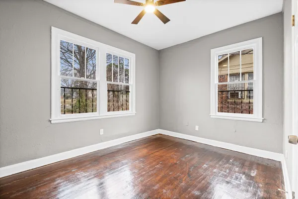 a view of an empty room with a window and wooden floor