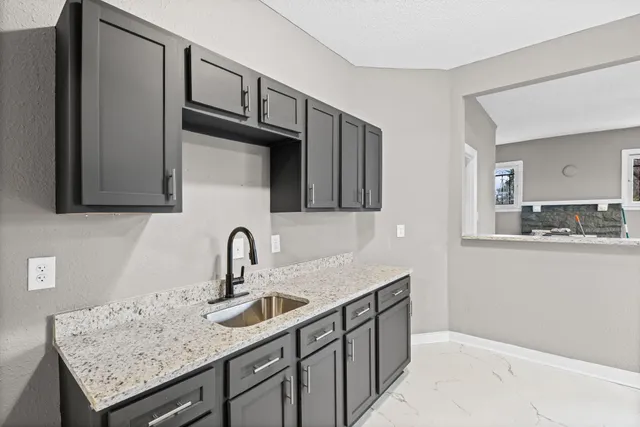 a kitchen with granite countertop a sink and cabinets