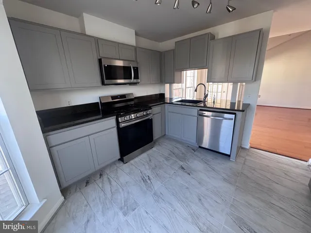 a kitchen with granite countertop wooden floors and stainless steel appliances
