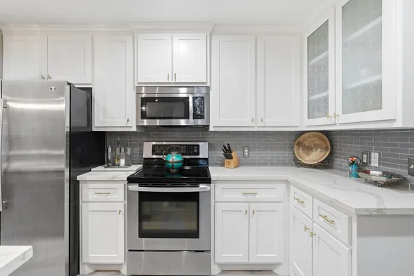 a kitchen with stainless steel appliances granite countertop a stove a sink a refrigerator a microwave oven with a dining table and chairs