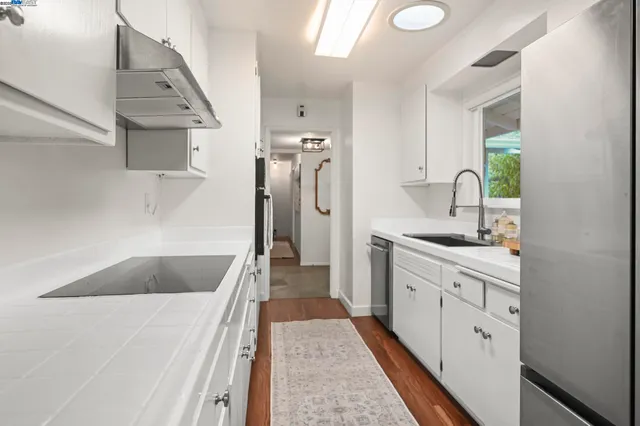 a kitchen with white cabinets and sink