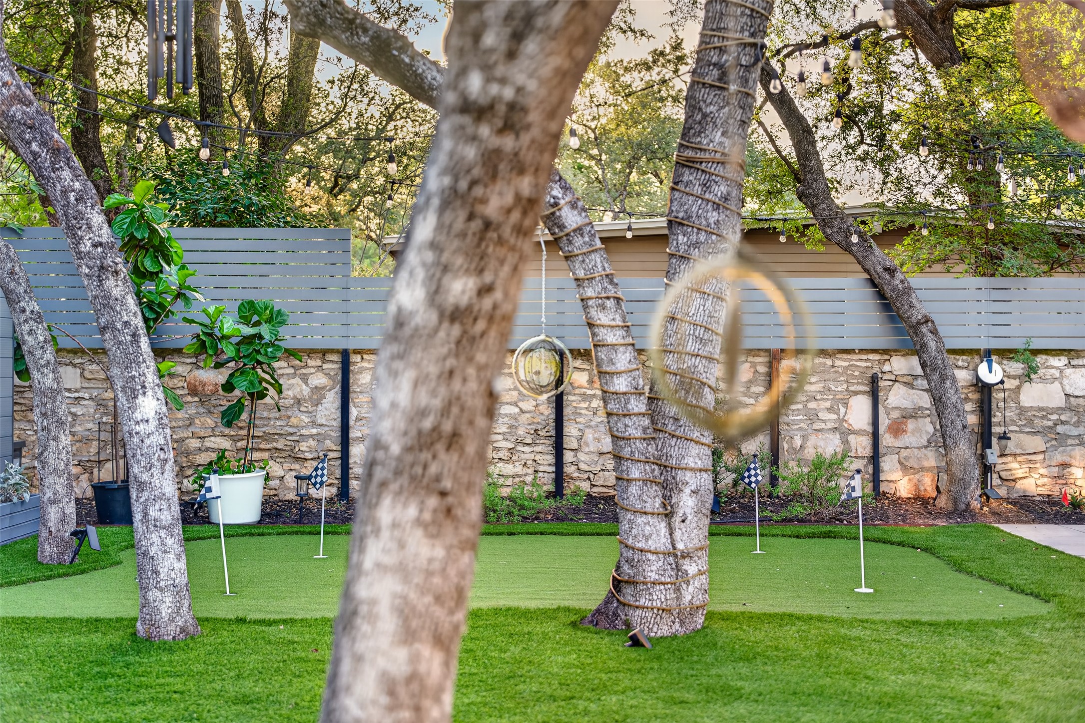 412 Ridgewood Road West Lake Hills, TX 78746 - Photo 28 of 40 A private backyard oasis features an artificial turf putting green, framed by mature trees and a stone retaining wall.