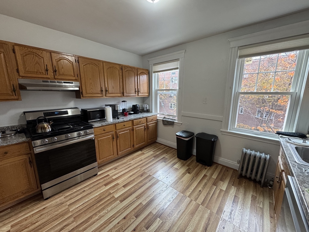 10 Alton Court, Unit 2 Brookline, MA 02446 - Photo 3 of 17 a kitchen with wooden floors and black appliances