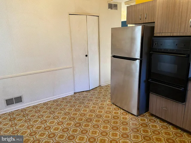 a view of a refrigerator in kitchen and an empty room