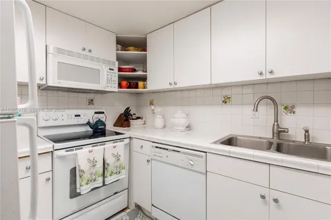 a kitchen with white cabinets and sink