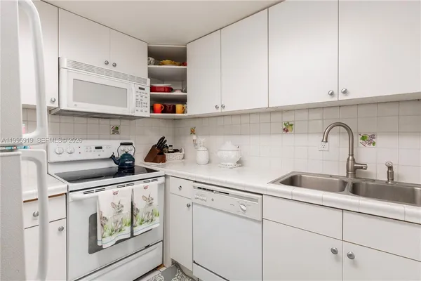 a kitchen with white cabinets and sink
