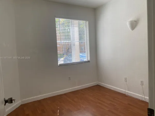 a view of an empty room with wooden floor and a window
