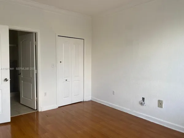 a view of an empty room with wooden floor and closet