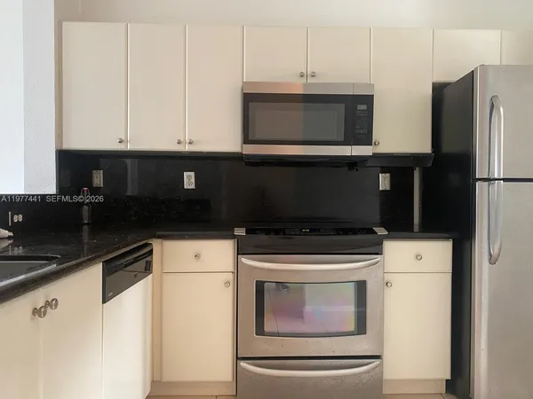 a kitchen with granite countertop white cabinets and stainless steel appliances