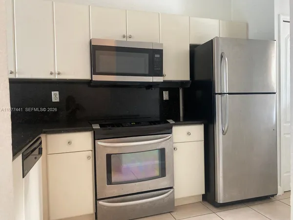 a kitchen with a refrigerator stove and white cabinets