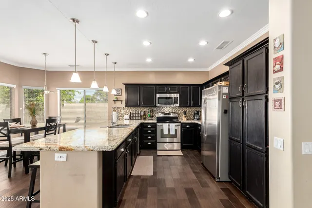 a kitchen with stainless steel appliances a refrigerator a sink a stove and white cabinets