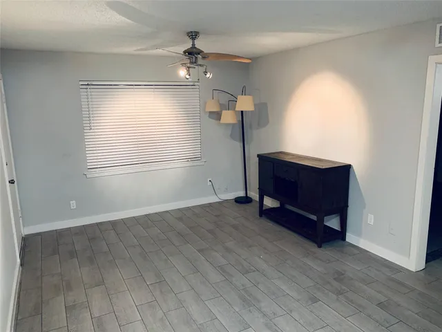an empty room with wooden floor cabinet and windows