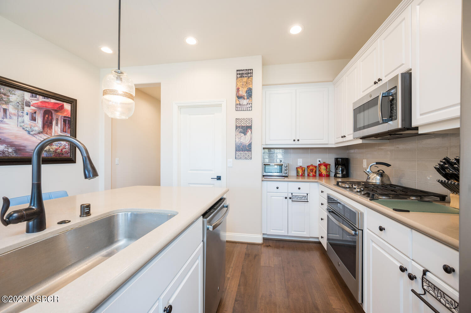 625 Agapanthus Way Santa Maria, CA 93455 - Photo 8 of 37 a kitchen with a sink dishwasher a stove top oven a refrigerator with white cabinets and wooden floor