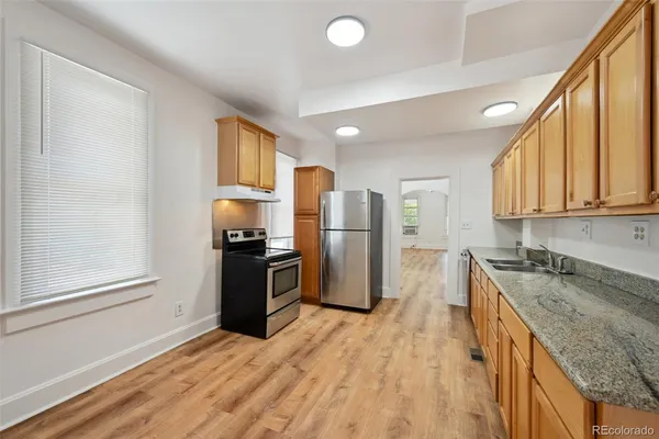 a kitchen with stainless steel appliances granite countertop a refrigerator a stove and a sink
