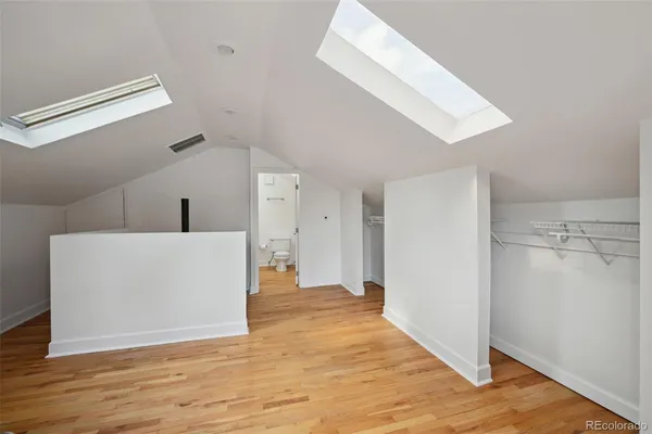 a view of a hallway to an empty room with wooden floor
