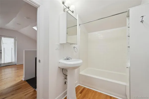 a bathroom with a bathtub a sink and wooden floor
