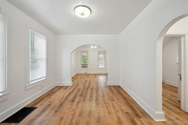 an empty room with wooden floor and windows