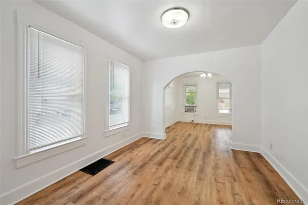 an empty room with wooden floor and windows