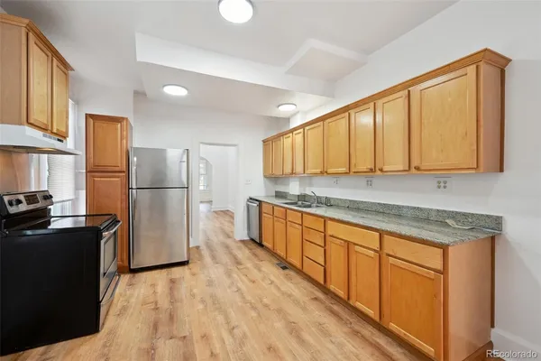 a kitchen with stainless steel appliances granite countertop a refrigerator a stove top oven and a sink